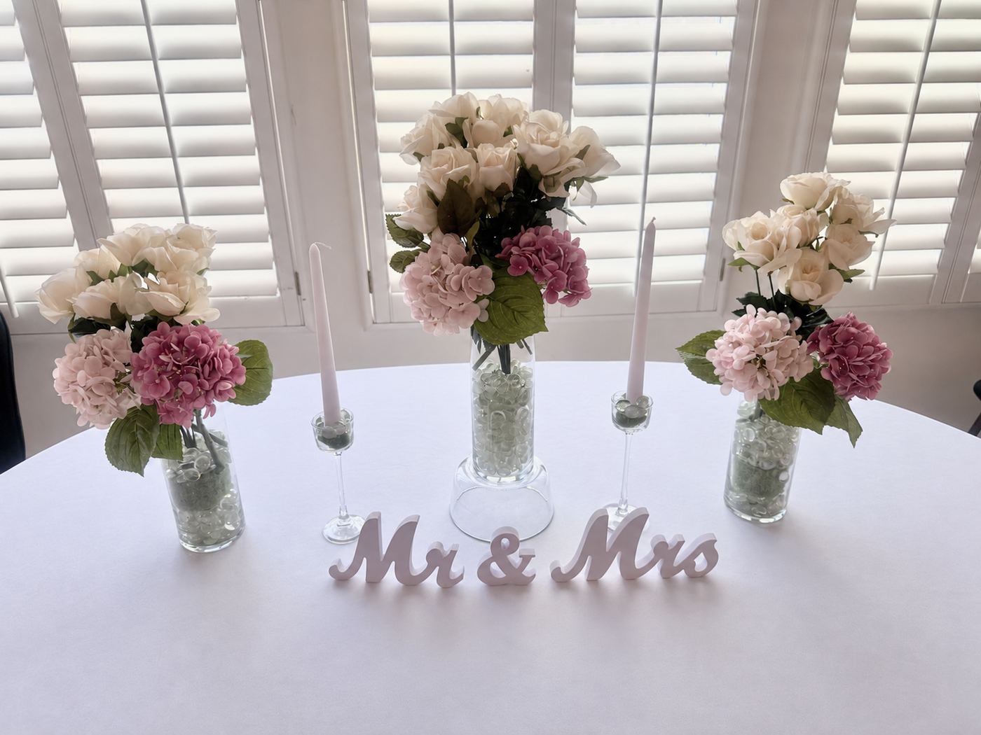 Round table with a Mr and Mrs sign and pink rose centerpieces